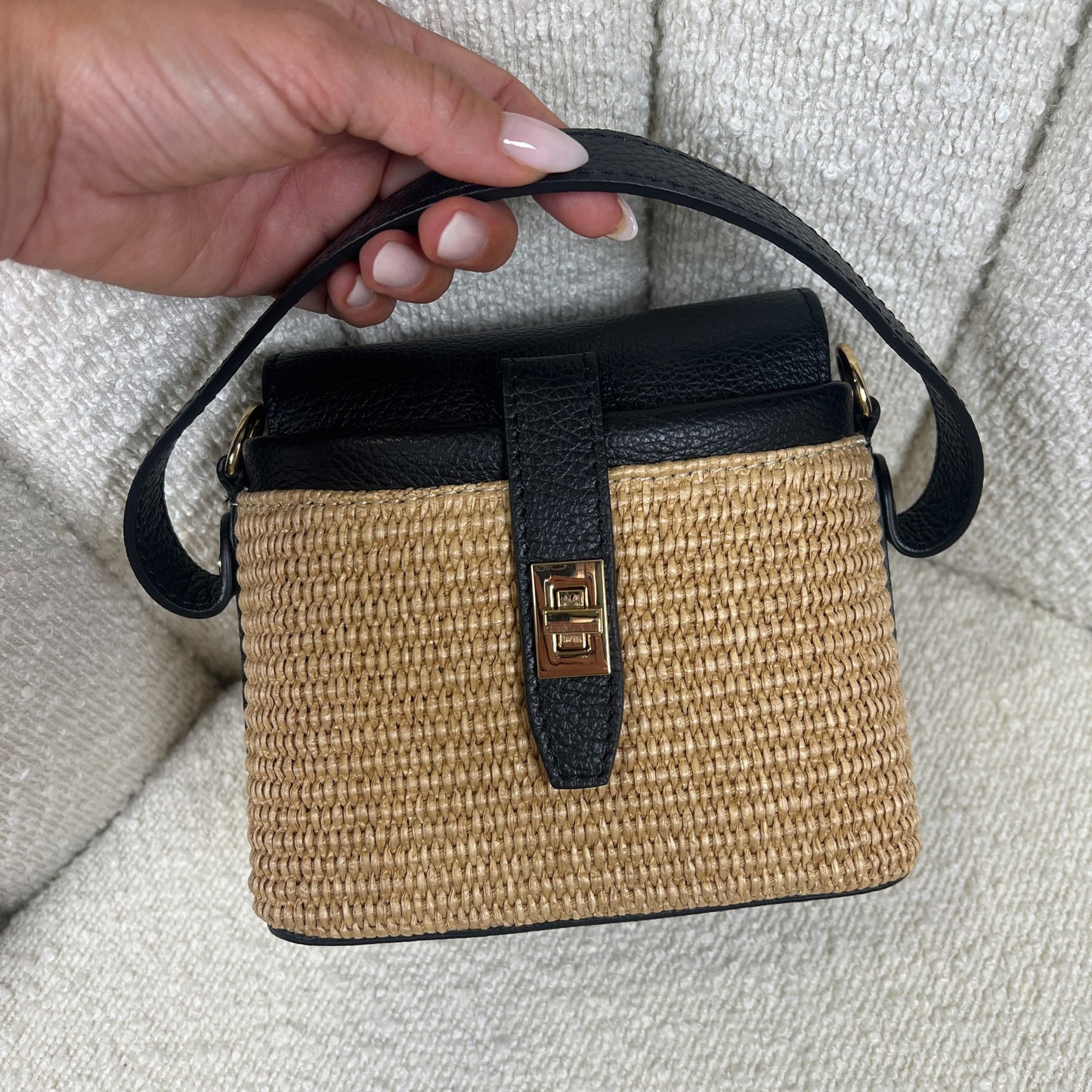 Borsa ÈCLAT Alma in rafia e pelle color nero, black vista con manico corto in mano su sfondo neutro