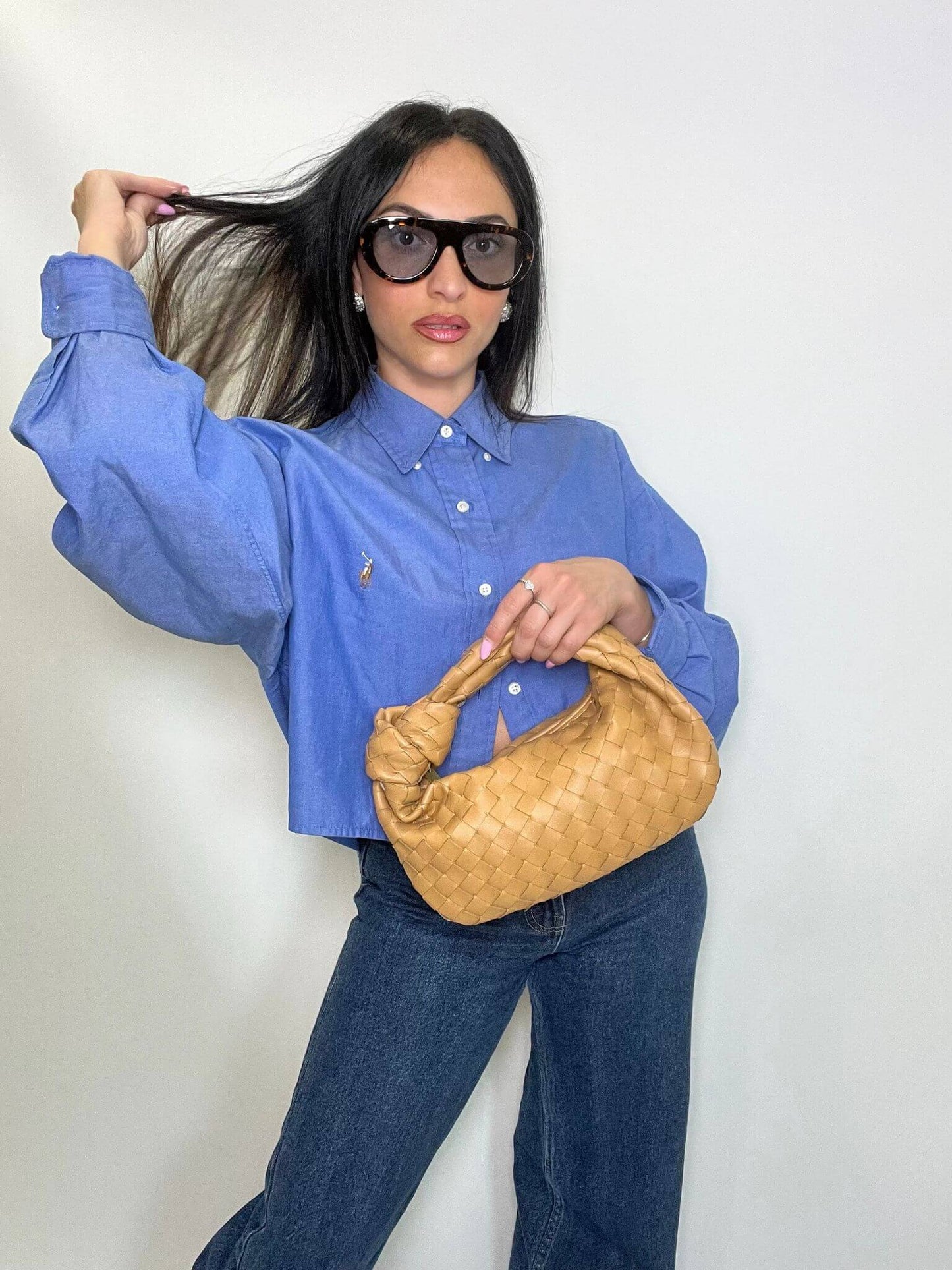 Modella con borsa Knot color cammello in pelle intrecciata, camicia denim e jeans – stile casual chic ÈCLAT.