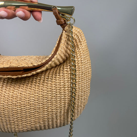 Dettaglio della borsa ÈCLAT in rafia naturale e pelle cognac con manico in metallo dorato e tracolla a catena