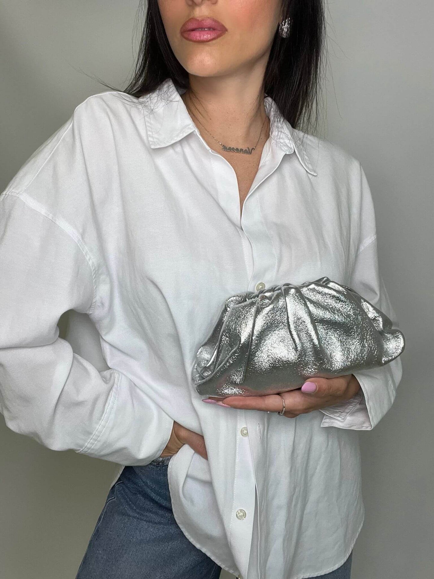 Modella che indossa mini pouch argento ÉCLAT Bags in stile Bottega Veneta, look elegante e raffinato