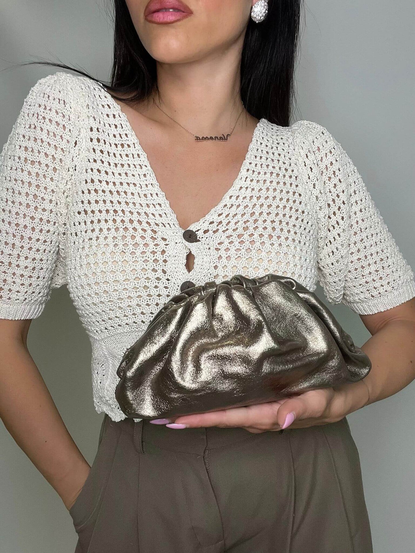 Modella che indossa mini pouch bronzo ÉCLAT Bags in stile Bottega Veneta, look elegante e raffinato