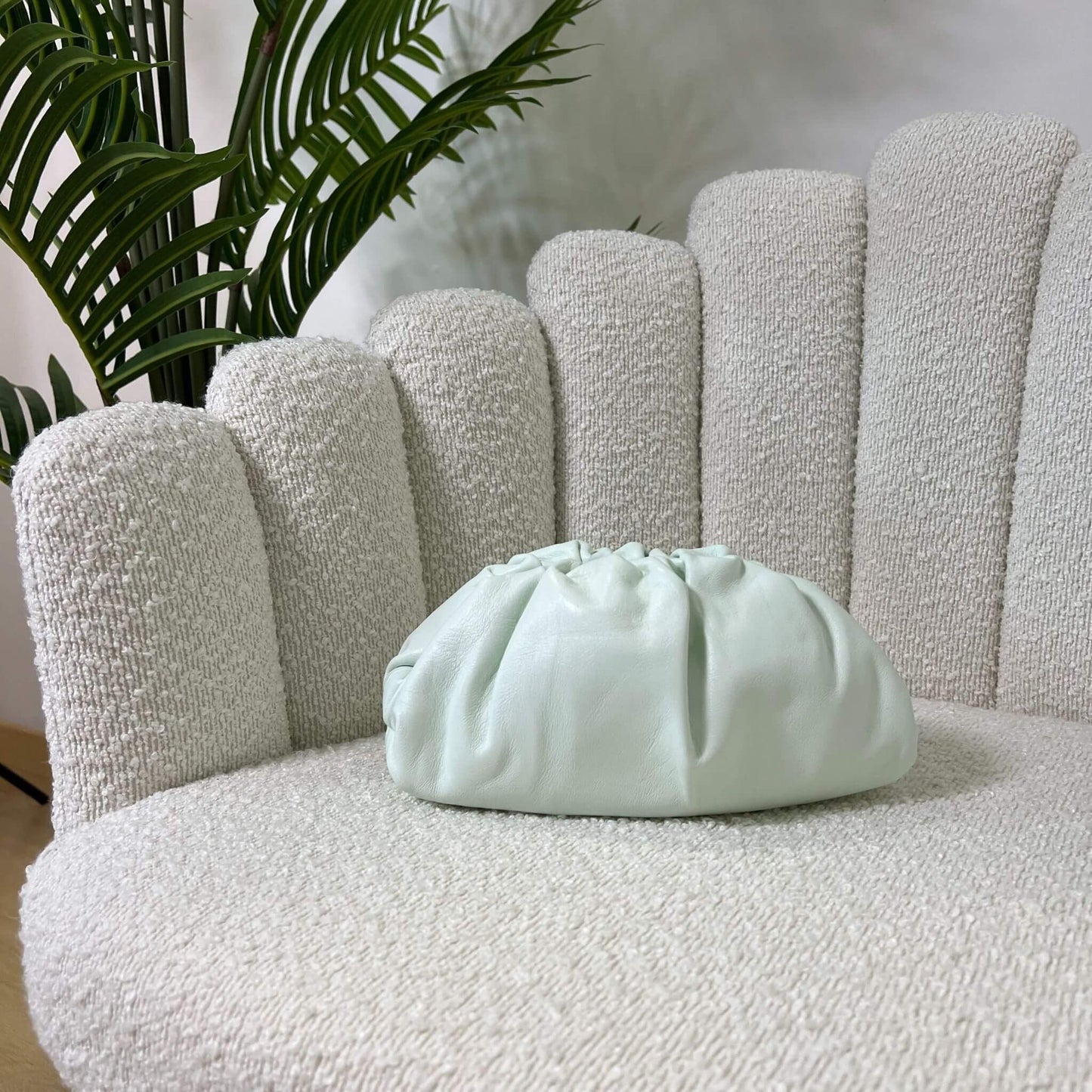 Mini pouch menta glaciale ÉCLAT Bags in stile Bottega Veneta su poltrona chiara, borsa elegante artigianale in pelle