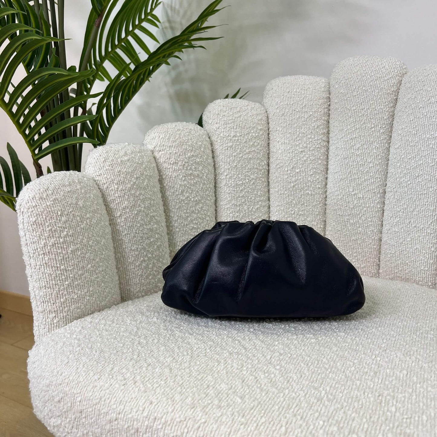 Mini pouch nera ÉCLAT Bags in stile Bottega Veneta su poltrona chiara, borsa elegante artigianale in pelle