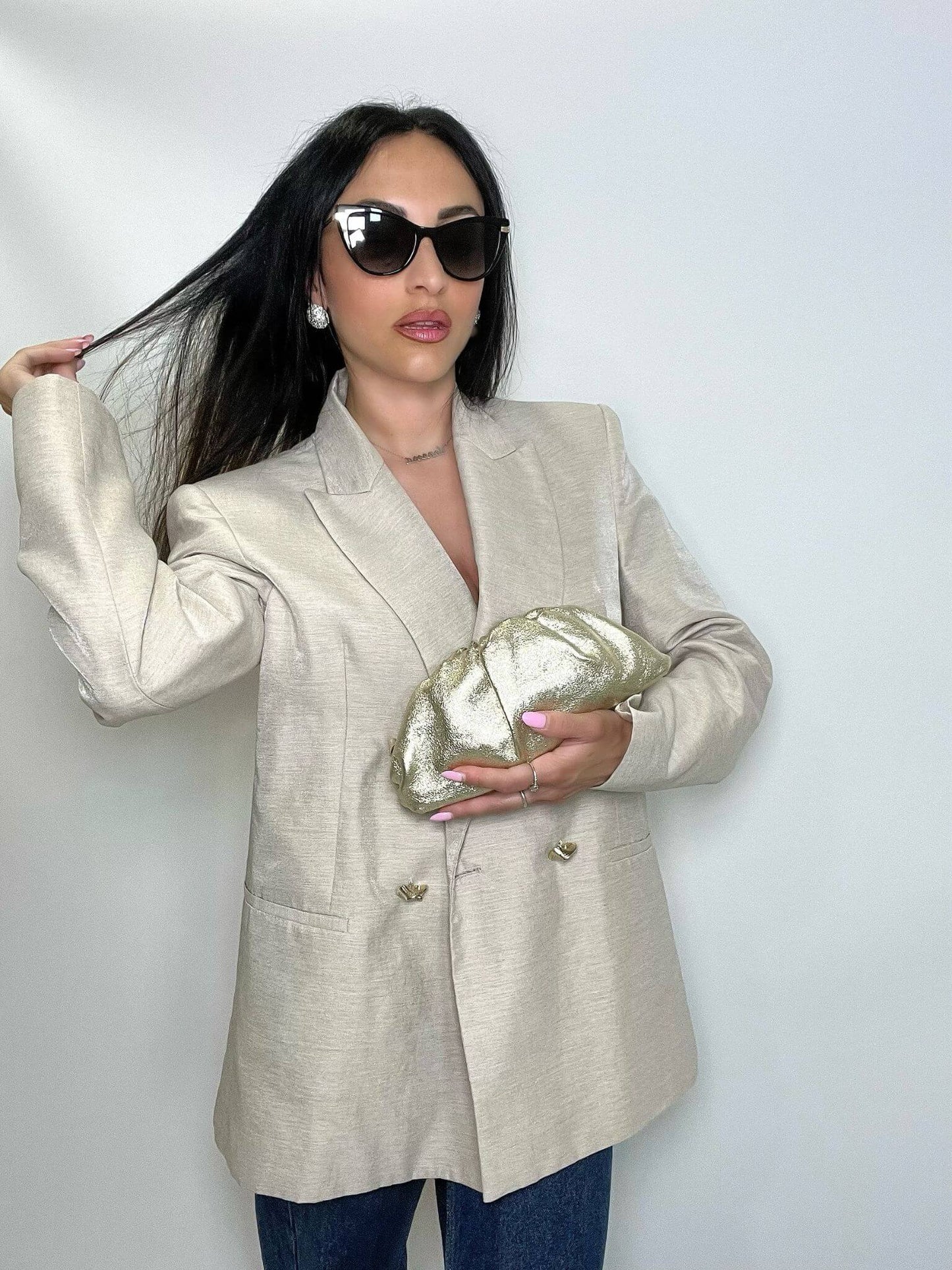 Modella che indossa mini pouch oro ÉCLAT Bags in stile Bottega Veneta, look elegante e raffinato