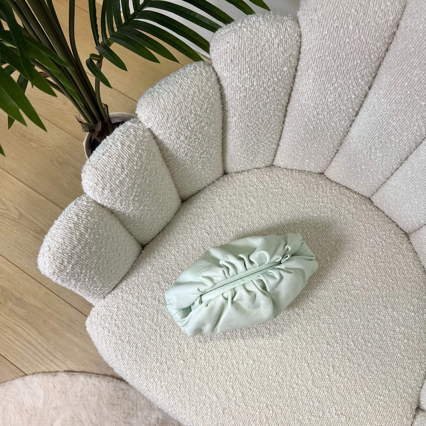 Mini pouch menta glaciale ÉCLAT Bags in pelle vista dall’alto su poltrona elegante, stile Bottega Veneta