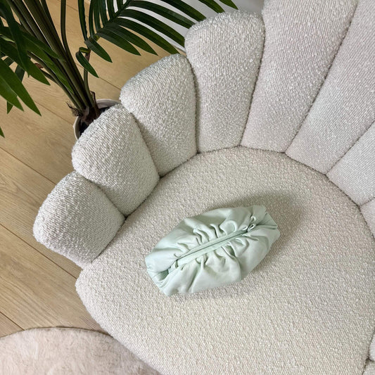 Mini pouch menta glaciale ÉCLAT Bags in pelle vista dall’alto su poltrona elegante, stile Bottega Veneta