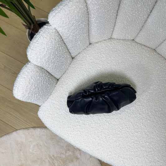 Mini pouch nera ÉCLAT Bags in pelle vista dall’alto su poltrona elegante, stile Bottega Veneta