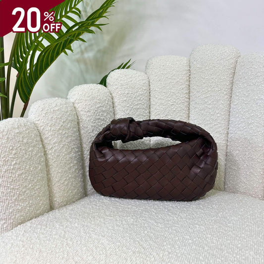Borsa color marrone fondant intrecciata con manico a nodo, modello Knot ÈCLAT, fotografata su poltrona elegante. simile alla jodie di bottega veneta