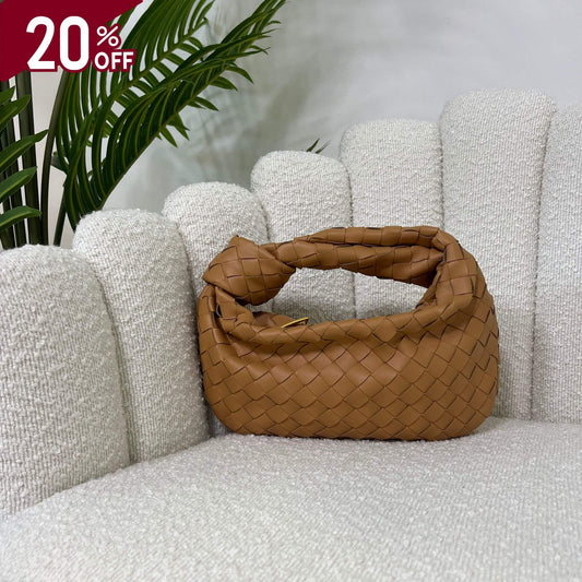 Borsa color cammello intrecciata con manico a nodo, modello Knot ÈCLAT, fotografata su poltrona elegante. simile alla jodie di bottega veneta